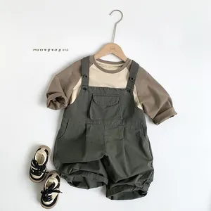 Detail of kids cotton long sleeve shirt with olive green bib overalls and canvas shoes
