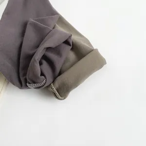 Close-up of durable knitted cotton fabric seams in dark purple and olive green for kids shirts