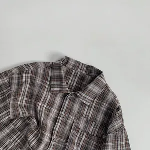 Close-up of brown and grey plaid flannel shirt featuring a neat collar and front button detail