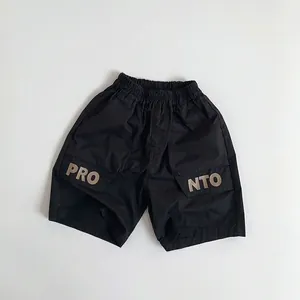 Detail of kids black cargo shorts featuring elastic waist and PRO letter print on pockets