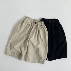 Detail view of elastic waist and pockets on minimalist cotton trousers for kids