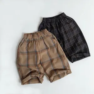 Detail of kids' plaid cotton shorts with elastic waistband and folded hem design