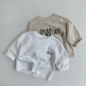 Close-up of cotton children's t-shirts with Maroon print in white and beige colors