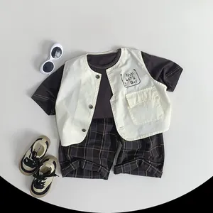 Detail of children's khaki plaid shorts and cream vest set with graphic print and pocket