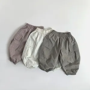 Close-up of children's cargo pants in grey, white, and charcoal with elastic waist and pockets