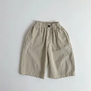 Detailed shot of elastic waist with black buttons on kids cotton trousers in khaki