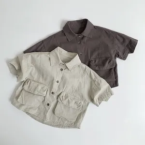 Detail of cotton utility shirts for children in beige and charcoal with flap pockets