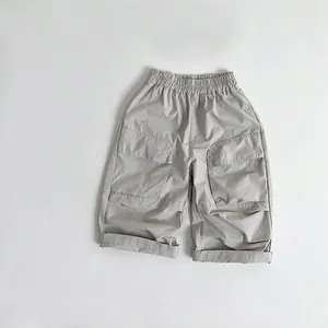 Detail of light gray kids' cotton pants featuring cargo pockets and elastic waistband