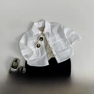 Tenue enfant avec chemise blanche à manches courtes, t-shirt kaki et short noir à plat