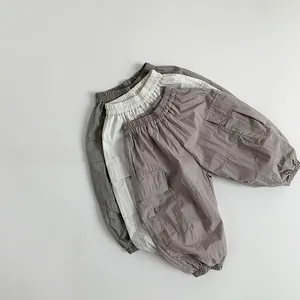 Flat lay of three breathable cargo pants for toddlers in grey, beige and purple colors