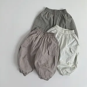 Three pairs of lightweight kids cargo pants in green, beige, and brown with large side pockets
