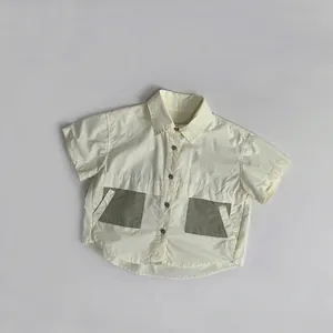 Detail of cream short-sleeved shirt with olive green square pockets and buttons