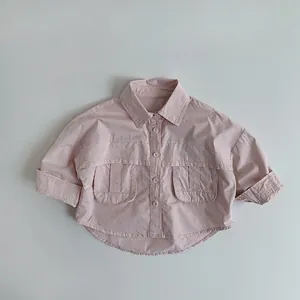 Détail d'une chemise rose clair à manches longues avec poches à rabat et ourlet arrondi