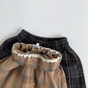 Flat lay of brown and dark grey plaid children trousers with elastic waist design