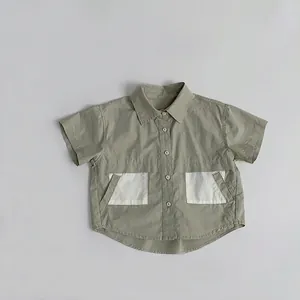 Detail of minimalist olive green cotton shirt with contrasting white pockets for boys