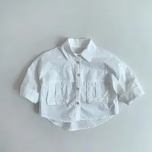 Détail de chemise blanche en coton pour enfants avec deux poches et boutons devant
