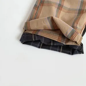 Detail of checkered cotton pants cuffs showing khaki and dark grey plaid patterns