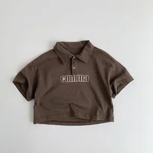 Détail d'un polo marron en coton pour enfants avec impression de lettres comma