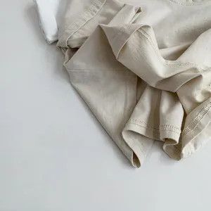 Close-up of cream cotton t-shirt fabric showing fine knit texture and stitching