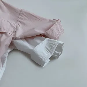 Détail rapproché des poignets de manches en coton doux sur chemises enfant rose et blanc
