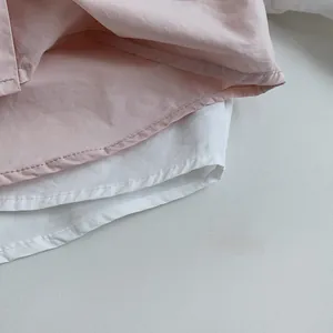 Gros plan des coutures à double aiguille sur des chemises en coton rose et blanc