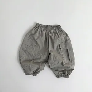 Detail view of elastic waistband and cargo pockets on light taupe toddler cargo pants