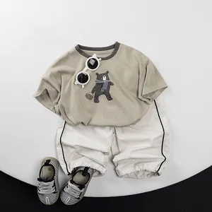 Flat lay of kids cotton outfit with bear print khaki t-shirt and white striped joggers