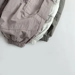 Detail of cargo pants elastic cuffs in grey-purple, cream and olive green textured fabric
