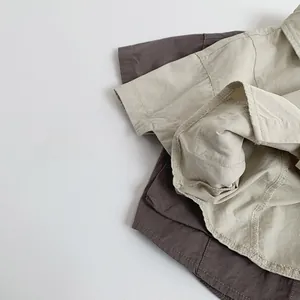 Detailed close-up of beige and dark gray cotton short sleeve shirts with fine stitching