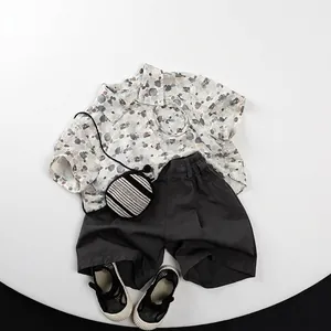Flat lay of kids summer outfit with pebble print short sleeve shirt and grey shorts