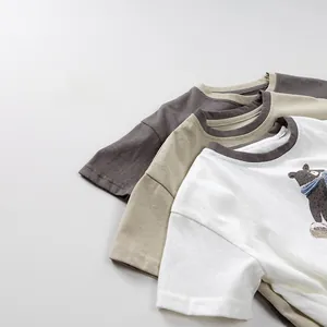 Close-up of three cotton kids' t-shirts in white, beige, and charcoal with bear print