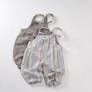 Détail de deux barboteuses bébé en coton avec carreaux marron, rayures et boutons en bois