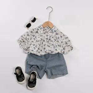 Detailed flat lay of kids floral print short sleeve shirt and frayed denim shorts outfit