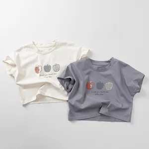 Close-up of cotton t-shirts for kids featuring apple prints and happiness slogans