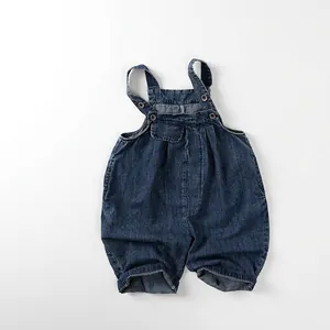 Détail d'une salopette en jean pour bébé avec délavage bleu foncé et boutons en métal
