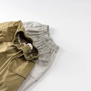 Dettaglio dell'elastico in vita e tasche cargo su pantaloncini da bambino verdi e grigi