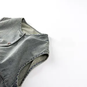 Detail of washed denim vest showing reinforced stitching and vintage metal button closure