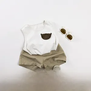 Flat lay of a cotton summer toddler outfit with white tank top and khaki shorts set