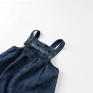 Gros plan détaillé de la salopette en jean pour enfant avec délavage et boutons métal