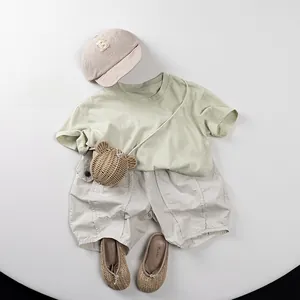 Kids cotton summer outfit with green T-shirt, beige shorts, cap and straw bear bag