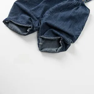 Détail d'une salopette en jean bleu foncé avec revers aux jambes et boutons en métal