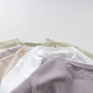 Close-up of stacked cotton t-shirts in pastel colors featuring durable crew neck stitching