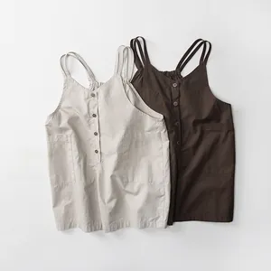 Détail de salopettes en coton et lin avec doubles bretelles et boutons à l'avant