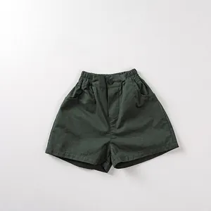 Detail of dark green cotton kids' shorts featuring elastic waist and side pockets