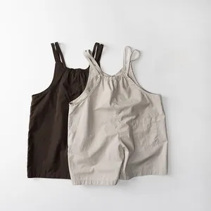 Détail de salopettes minimalistes en coton et lin avec fines bretelles et poches arrière