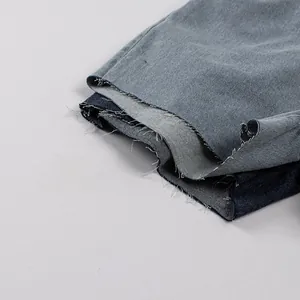 Détail de l'ourlet effiloché du short en jean montrant les bords bruts et le délavage bleu