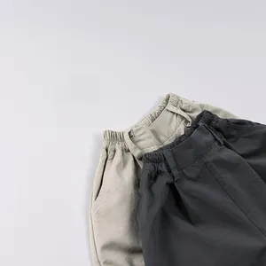 Dettaglio di pantaloncini in cotone per bambini con elastico in vita e tasche kaki e grigio
