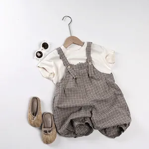 Salopette grise à carreaux pour enfant avec t-shirt blanc et accessoires à plat
