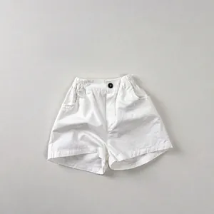 Close-up of white cotton shorts featuring elastic waist with button detail and side pockets