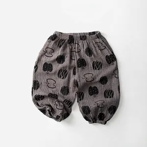 Detail of grey-brown cotton kids pants with black fruit print and elastic waistband